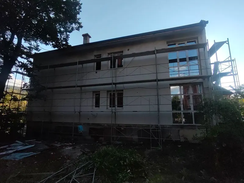 Двуетажна къща със скеле в процес на саниране